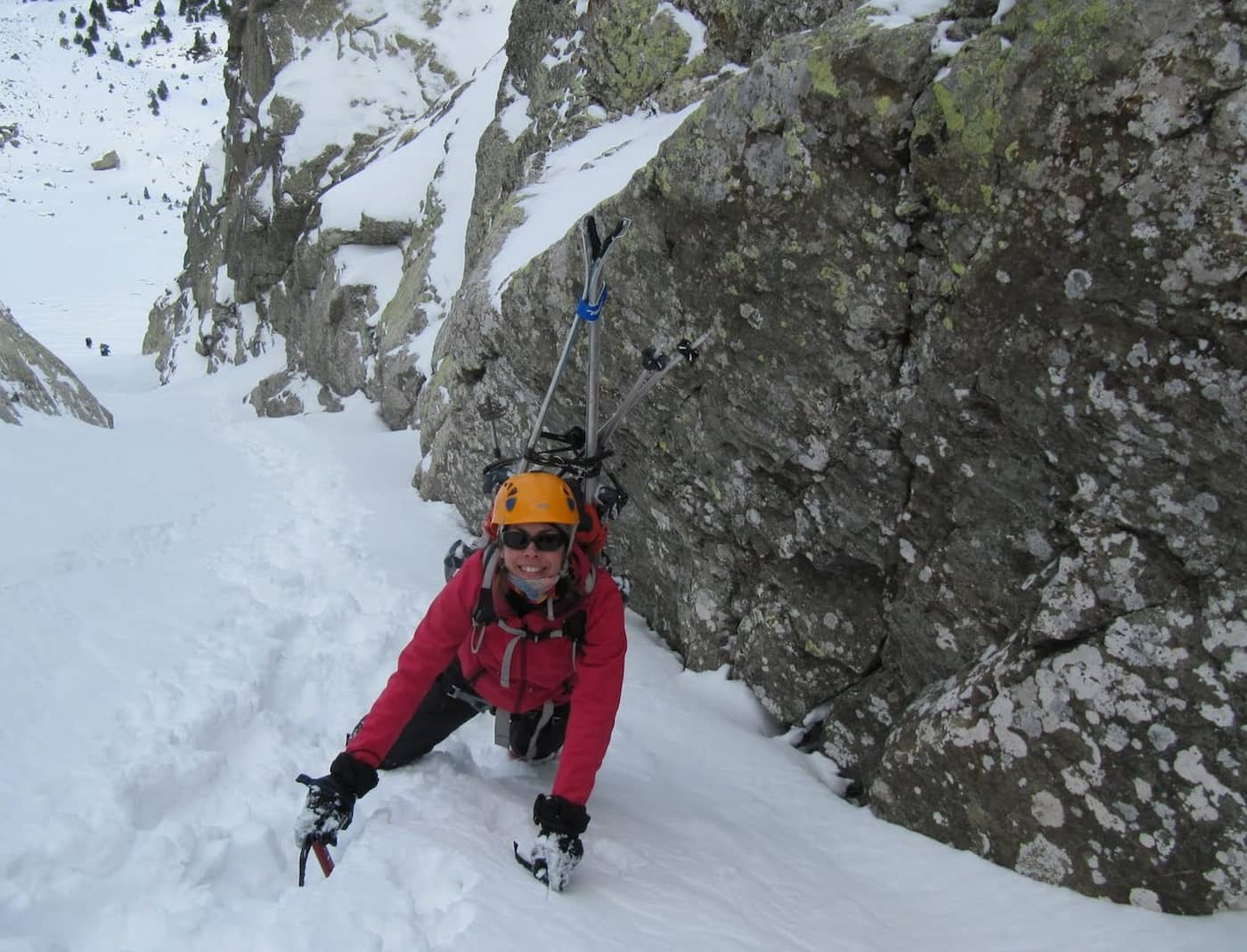 Carme escalando un canal nevado en esquí de montaña, esquís a la espalda